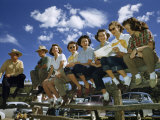 Men and Women on Vacation Sit on a Corral Fence to Watch a Rodeo