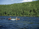 Men Paddle a Canoe Through River Rapids