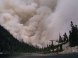Helicopter Carrying Water from a River to Fight a Forest Fire
