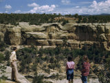 Tourists Stand on a Canyon Rim Overlooking Ancient Cliff Dwellings