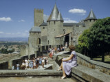 Woman Sitting on Stone Wall Watches People Touring Castle's Ramparts
