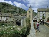 People in Riverside Village Walk across an Old Bridge