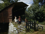 Women Riding Bicycles Stop to Admire Scenery Near a Covered Bridge