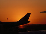Airplane Tail and Approaching Plane Silhouetted in the Setting Sun
