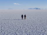 Two Tourists Walk across the Endless Salt Crust of Salar De Uyuni  the Largest Salt Flat in World