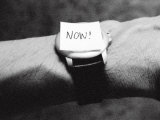 The Word Now as a Reminder Attached to a Watch on a Male Arm