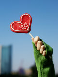 Woman's Hand Holding Up a Red Heart-Shaped Lollipop