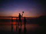 Father with His Children Tosses a Ball on the Beach at Dusk