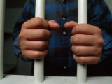Hands Hold onto Jail Bars in a Montgomery County  Maryland Jail Cell