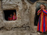 Displaced Girls Smile as They Look Out from a Shanty  in a Refugee Camp in Kabul  Afghanistan