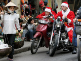 Vietnamese Men Dressed as Santa Claus Wait on their Motorbikes on a Street in Hanoi  Vietnam
