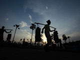 Laborers Silhouetted Against the Setting Sun while Working at a Brick Kiln in India