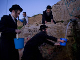 Ultra-Orthodox Jewish Men Stand Next to a Well as They Fill Canisters with Water in Jerusalem