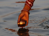 Woman Praying on the Banks of the River Ganges Fills Water into a Copper Vessel for a Ritual