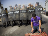 Palestinian Worshipper Prays Outside Jerusalem's Old City While Israeli Forces Stand Guard