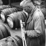 Customs Official Checks the Volume of Wine in a Barrel