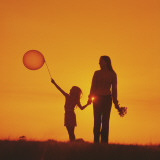 Mother and Daughter Walking at Sunset Holding Balloon