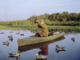 Hunter Sitting in Canoe Surrounded by Duck Decoys