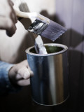 Close-Up of a Person's Hand Holding a Paintbrush and a Paint Can