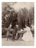 Monsieur et madame Salles et une autre personne assis autour d'une table sous un saule pleureur