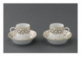 Deux tasses et soucoupes à café décorées de guirlandes et de fleurettes dorées