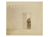 Jeune femme entrant dans une cour par une porte donnant sur un jardin