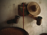 A Straw Hat  Straw Baskets and a Belt Hang on a White Wall