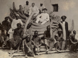A Group of Men Sit Atop a Pile of Ivory Tusks