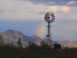 A Windmill on a Ranch with a Rainbow and Mountain Scenery