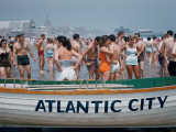 Throngs of Swimmers Stroll Behind a Wooden Lifeboat on the Beach