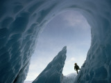 A Climber Stands Near the Opening of an Ice Cave