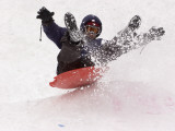 A Man Sleds Down a Hill During a Snowstorm