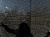 Shadow of a Woman Pointing to a Name on the The Vietnam Memorial