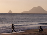 A Child Running and Another Playing on a Beach Along the Shoreline