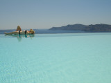 A Woman Lays at an Infinity Poolside Overlooking the Aegean Sea