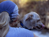 Woman Holding a Pet Dog  Watching an Unseen Kayaker