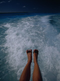 A Woman's Feet Dangle over the Churning Wake of a Motorboat