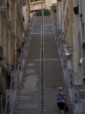 A Woman Walks Up a Steep Stairway Between Buildings