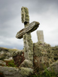 An Old Moss-Covered Cross Stands Amid Rocks in a Graveyard