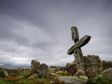 An Old Moss-Covered Cross Stands Amid Rocks in a Graveyard