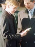 Prince Charles looks on after Prince William receives a present from a young local girl at the trad