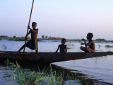 Three Boys Play on a Canoe (Pirogue) on the River in Mopti