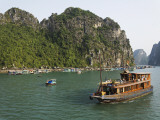 Tourist Cruise Boat Passing Typical Floating Village Among Limestone Islands of Halong Bay