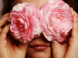 Young Girl Holding Camellia Flowers over Her Eyes