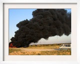 A Civilian Car Passes by a Burning Oil Pipeline Near Baqouba