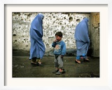 A Young Afghan Refugee Boy Stands in a Pair of Adult's Shoes
