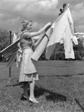 Woman  Housewife  is Outdoors  Hanging Clean Fresh Laundry on Clothesline