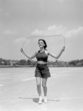 Smiling Teenage Woman Jumping Rope For Exercise Wearing Shorts and Polka Dot Halter Top