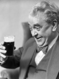 Elderly Man Holding and Staring at a Glass of Beer  Smiling and Laughing With a Happy Expression