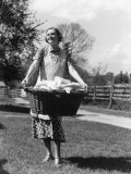 Woman Wearing Apron  Carrying a Wicker Basket of Clean Laundry Outdoors